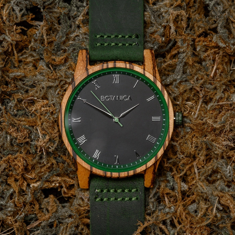 Wooden watch with green strap and black dial on a textured surface
