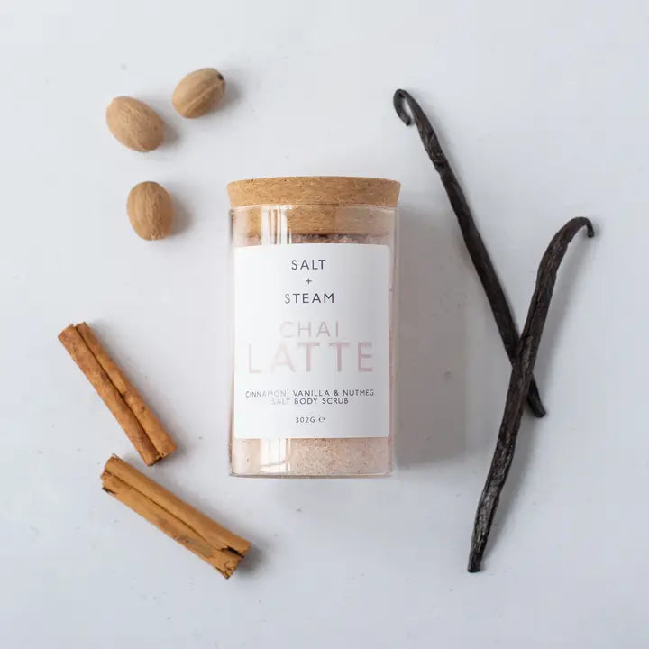 Jar of Salt & Steam Thai Latte scrub with vanilla beans, cinnamon sticks, and nutmeg on a white background