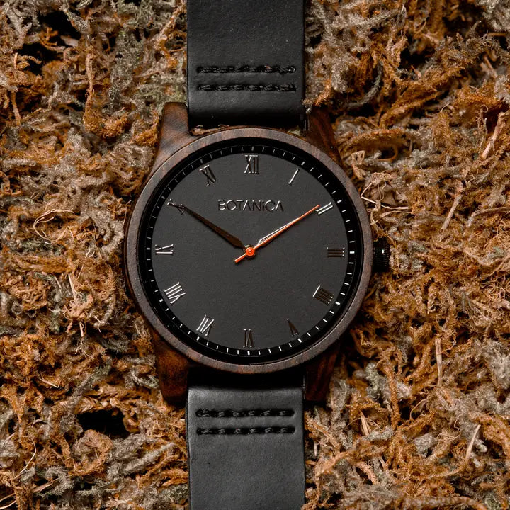 Black watch with a leather strap on a textured brown background