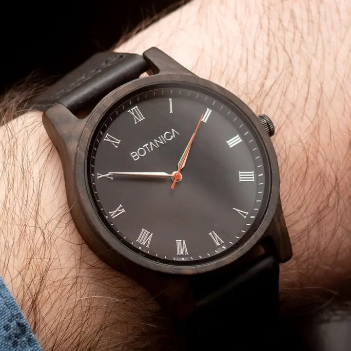 Black wristwatch with 'BOTANICA' brand on a person's wrist