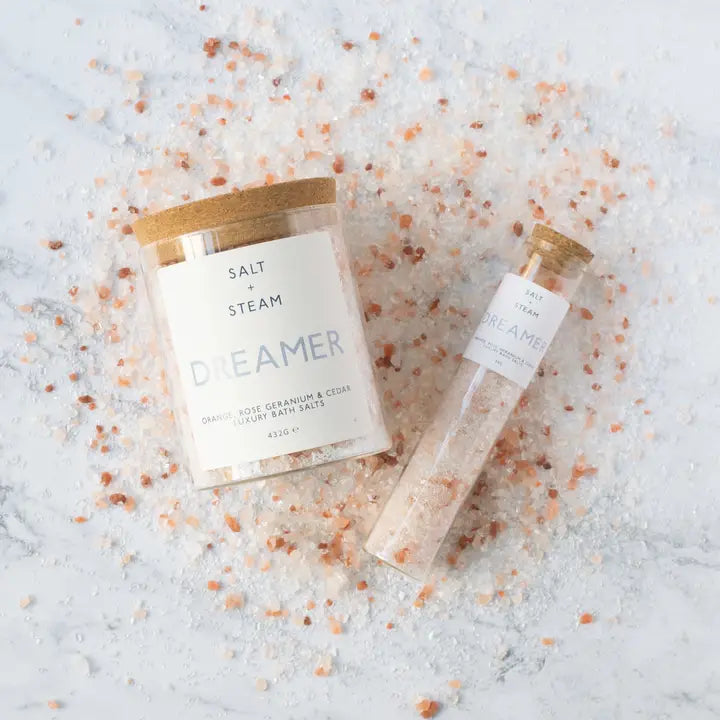 Bath salt packaging with 'Salt & Steam' branding on a textured surface with bath salts.
