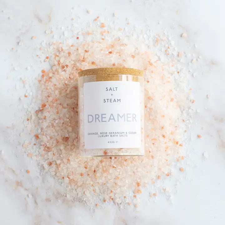 Bath salt with a 'Salt & Steam Dreamer' candle on top, surrounded by pink Himalayan salt crystals.