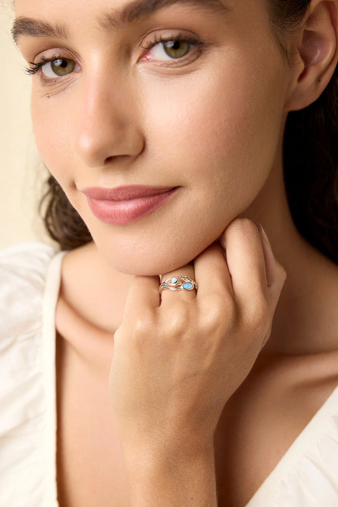 Close-up of a woman wearing a ring with a visible gemstone on a neutral background