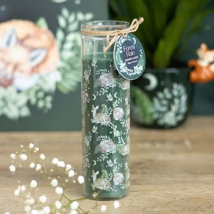 Decorative candle with floral design and 'Forest Rain' label on a wooden surface.