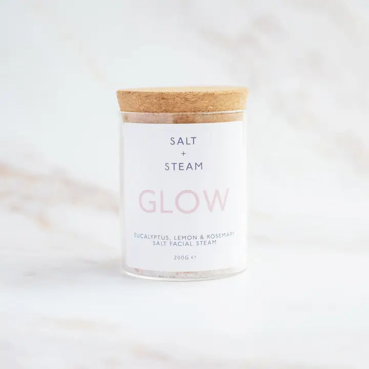 Glass jar with wooden lid labeled 'Salt + Steam Glow' on a white background