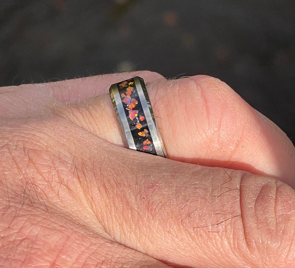 Close-up of a hand wearing a ring with a colorful band against a blurred background