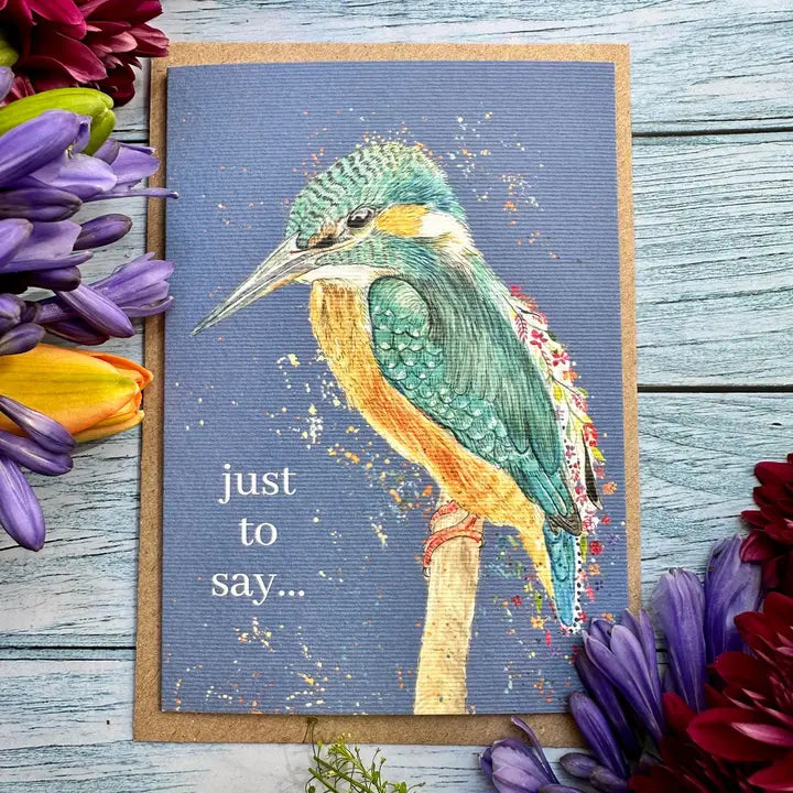Card with a colorful bird illustration and flowers on a wooden surface