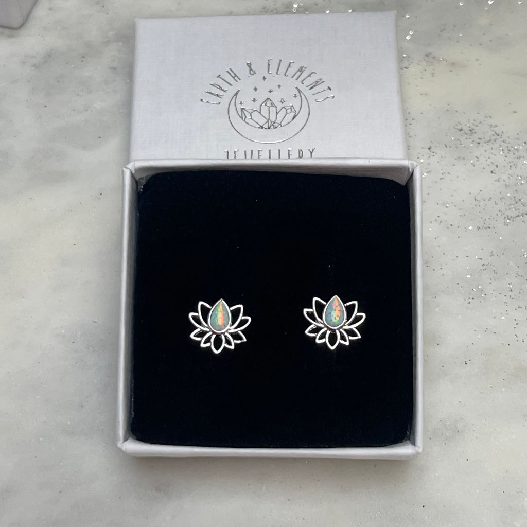 Lotus flower earrings in a branded box on a light gray surface