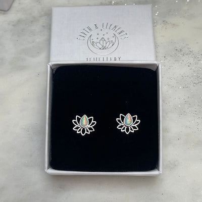 Lotus flower earrings in a branded box on a light gray surface