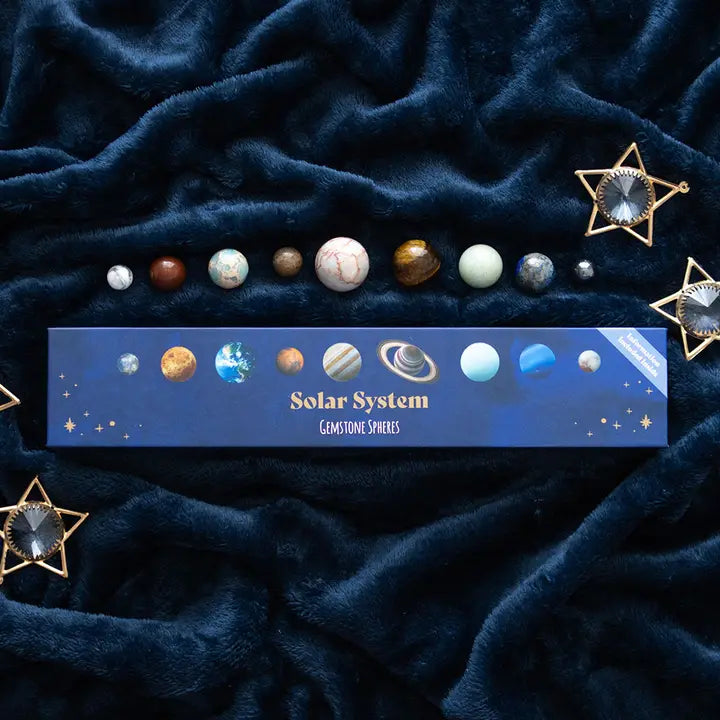 Solar system gemstone spheres on a dark blue textured fabric background