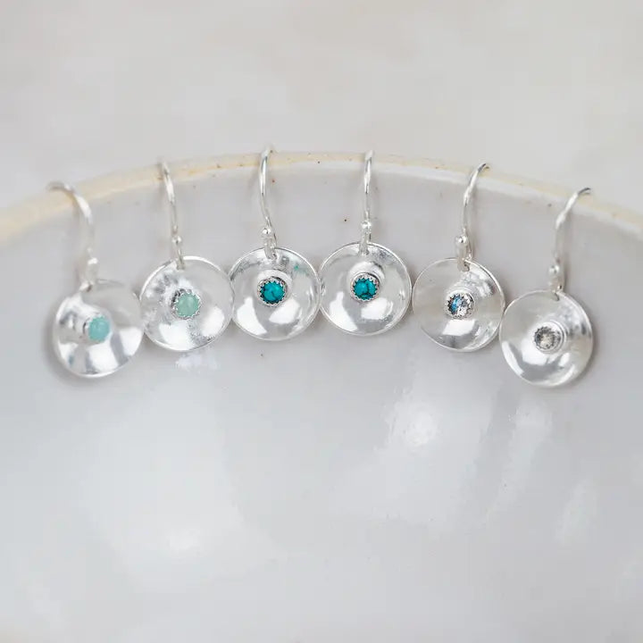 Set of silver earrings with gemstones on a white dish