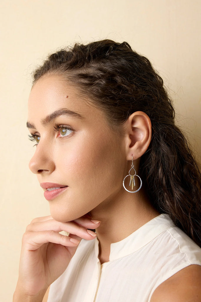 Woman wearing silver hoop earrings against a beige background