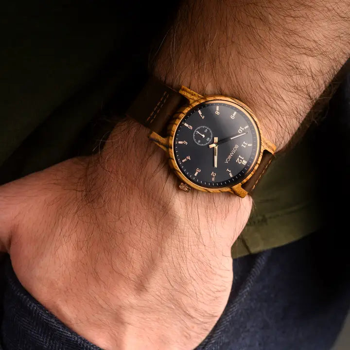 Gold wristwatch with a black face on a wrist against a dark background