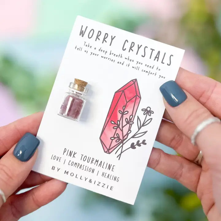 Worry crystals packaging with pink tourmaline crystal and bottle, held by a person.