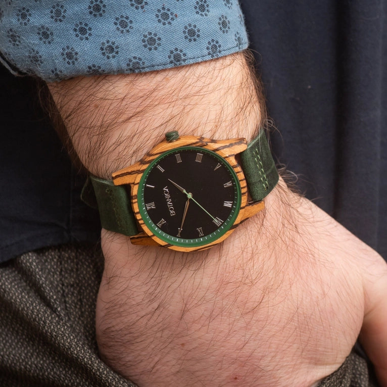 Wooden watch with green strap on a wrist, close-up view.